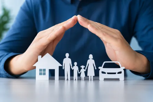 Mãos a proteger símbolos de casa, família e automóvel, representando soluções de seguros e proteção financeira.